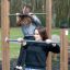 Zwei Frauen benutzen Reckstangen aus Holz im Outdoor-Fitnessbereich.