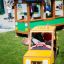 Kinderspielplatz mit Bus Spielhaus und gelbem Taxi-Spielauto auf dem Rasen