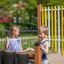 Spielplatz Schlagzeug aus Holz mit zwei spielenden Kindern in Sommerkleidung