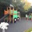 Großer Traktor Spielhaus mit Rutsche und Kletterwand auf dem Spielplatz aus Holz und grünem Kunststo