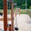Sand & Wasserspielanlagen III mit Kinder-Schaukel im Sandspielplatz.