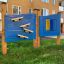 Rennbahn Spieltafel mit blauen Tafeln und gelben sowie blauen Spielkugeln auf einem Spielplatz.