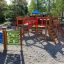 Rennbahn Spieltafel auf einem Kinderspielplatz aus Holz mit Sandboden und verschiedenen Kletter- und