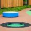Rundes trampolin (100 cm) im Kinderspielplatz eingebettet im Boden mit grünem Netz und schwarzem Ran