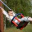 Kind auf Holzbabyschaukel an Spielplatz mit Grünfläche