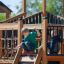 Windsor Spielanlage mit Rutschen aus Holz auf Spielplatz mit zwei Kindern beim Spielen