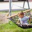 Kind child sits on Doppelhängematte (Metall) net swing in playground.