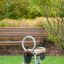 Fahrrad Federwippe mit Holzsitz und Metallgriff für Spielplatz, auf grünem Rasen.