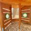 Holzstruktur vom Spielplatz-Element Schiff Modern Nature mit runden Fenstern und Holzschnitzelboden.