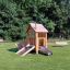 Tambora Spielhaus mit Rutsche Eco aus Holz auf grünem Spielplatz mit Bänken im Hintergrund