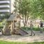 Tambora Spielhaus mit Rutsche Eco aus Holz auf einem Spielplatz im Freien.