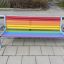 Bunte Bank mit Metallrahmen auf Spielplatz, mehrfarbig gestaltete Sitzfläche und Lehne aus Holzlatte