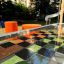 Hpl Bank & Spieltisch mit Schachbrettmuster und orangen Sitzhockern im Aussenbereich.