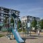 Spielanlage Köln mit Rutschbahn und Kletterelementen auf einem modernen Spielplatz vor Wohngebäuden.