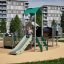 Spielplatzgerüst Festung mit Rutsche im urbanen Umfeld mit spielenden Kindern