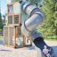 Breezekiste mit Rutsche, modernes Holzspielgerät mit geschlossener Metallrutsche auf Spielplatz