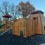 Spielanlage Skandinavische Hochburg aus Holz mit Rutsche und Kletterelementen auf einem Spielplatz.