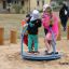 Kinders spiele am Biene Drehkarussell im Sand auf dem Spielplatz.