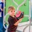 Chind spielt mit em Sensory Box an em Spielplatz-Element.