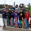 Kinders mit Skateboards stehen auf einer Rampe im Skatepark mit Helmen.