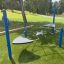Balancier Spielplatz Netz mit blauen Pfosten und Kletternetz auf grünem Kunstrasen im Park.