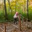 Kind spielt auf dem Altweibersommernetz Horizontales Kletternetz im herbstlichen Waldspielplatz.