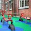 Spielplatz mit Wetpour 40 Fallschutzbelag und roten Wippen aus Metall und Reifen in städtischer Umge