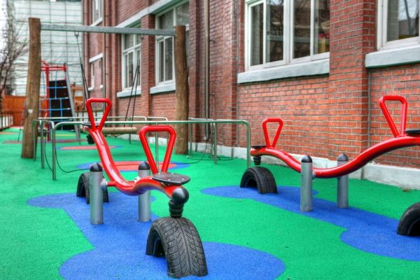 Spielplatzgeräte Wetpour 60 mit rotem Wippsitz und Sicherheitsbelag aus Gummi auf Boden.