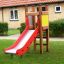 Kleiner Spielturm mit Rutsche aus Holz im Garten, rote Rutsche auf grünem Rasen