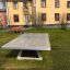 Betontischtennisplatte freistehend im öffentlichen Park mit Bank und Wohngebäude im Hintergrund