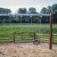Spielplatz mit Schaukelsitz: Sicherheitssitz und einfachem Holzschaukel neben Zaun auf Sandboden.