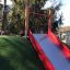 Hangrutsche Breit SLW210 mit rotem Geländer auf grasbedecktem Hügel im Spielplatz.