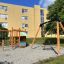 Kramladen Klettergerüst mit Rutsche und Schaukel aus Holz auf Spielplatz vor Wohnhaus