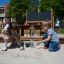 Kinder spiele im Barrierefreie Sandkasten mit Holzelementen und Wasserpumpe.