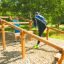 Kinder und Jugendlich benutzen das Hindernisrennen aus Holz im Outdoor-Spielplatz.