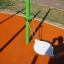 Hängematte Schaukel mit weissem Sitz und grünen Metallpfosten auf Spielplatz mit oranger Gummimatte