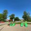 Umbrela Sonnenschutz auf Spielplatz Sandbereich mit grünen Liegestühlen