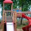 Twister Spielanlage mit Rutsche aus Holz und rotem Dach auf Kinderspielplatz
