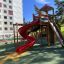 Twister Spielanlage mit roter Rutsche und Klettergerüst auf modernem Spielplatz