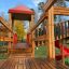 Weltraumstation mit Spieltürme, Holzbrücke und roter Spiralrutsche im Kinderspielplatz