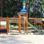 Weltraumstation mit Spieltürme und Spiralrutsche aus Holz im Outdoor-Spielplatz bei Sonnenschein