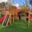 Weltraumstation mit Spieltürme und Spiralrutsche aus Holz auf Spielplatz mit künstlichem Gras