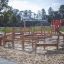 Fitness Anlage Spielplatz-Parcours aus Holz mit Kletterelementen und Sandboden.