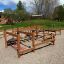 Kleine Fitnessanlage aus Holz mit Kletternetzen und Balancierbalken auf Spielplatz.